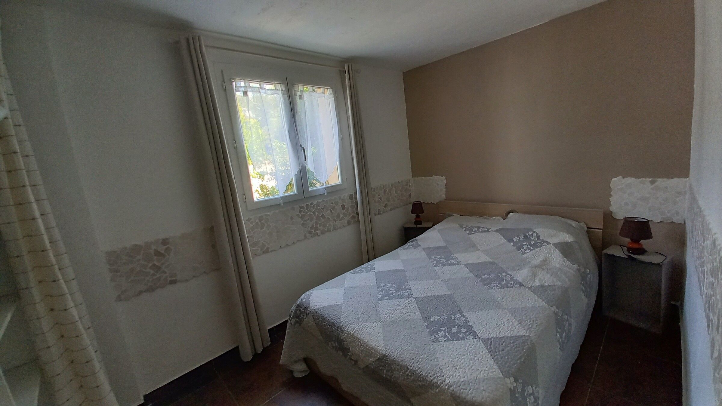 La chambre au lit double, fenêtre ouverte sur la végétation