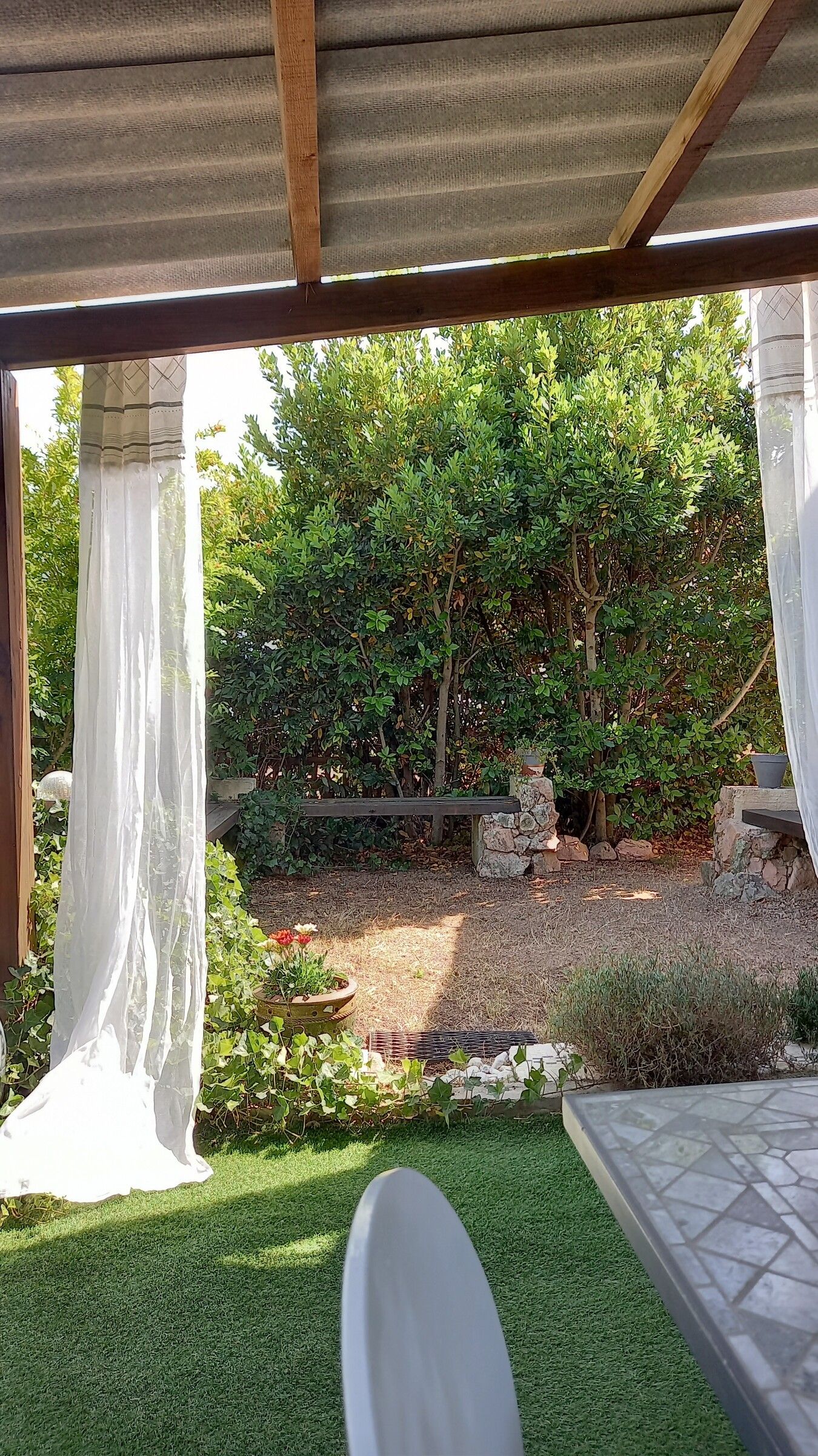 Vue depuis la terrasse vers le jardin, encadrée par deux voilages